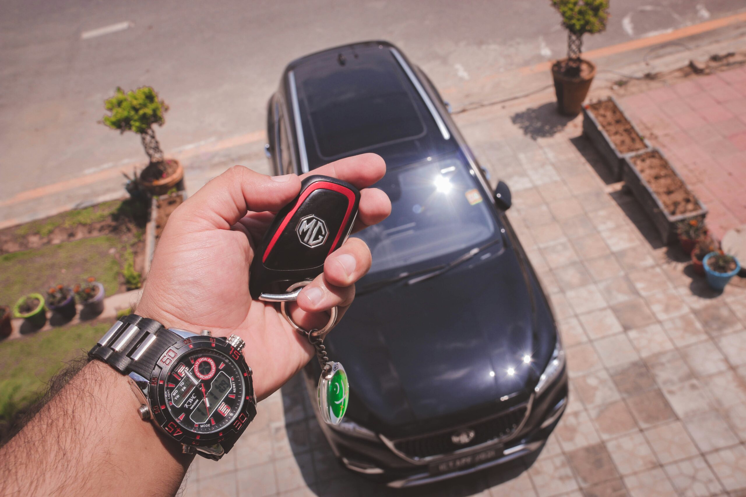 person holding black and round keyless go key from MG car